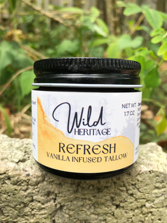 A jar of Wild Heritage 'Refresh' vanilla infused tallow, placed outdoors with a natural background.